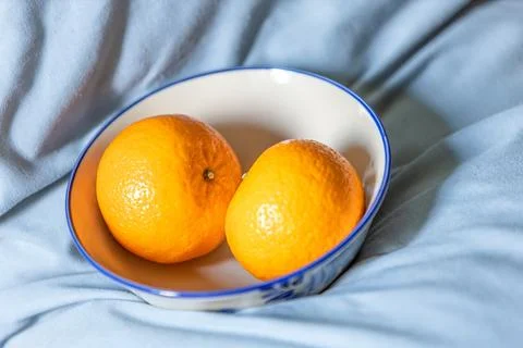 Two oranges fruit on a white ceramic bowl. Stock Photos