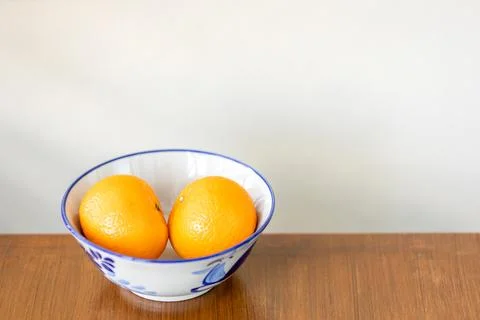 Two oranges fruit on a white ceramic bowl. Stock Photos