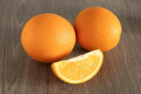 Two oranges next to them is a slice of cut on a wooden background Stock Photos