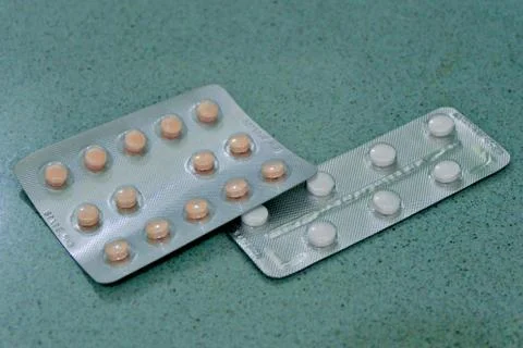 Two packages of pills on a teal surface Stock Photos
