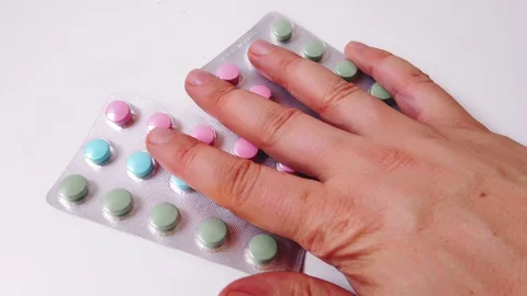Two packs of multi-colored pills with vitamins on a white table. Stock Footage 128314057