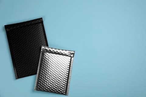Two padded envelopes with bubble wrap on turquoise background, flat lay. Spac Stock Photos