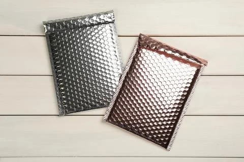 Two padded envelopes with bubble wrap on white wooden background, flat lay Stock Photos