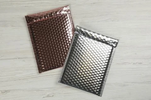 Two padded envelopes with bubble wrap on white wooden background, flat lay Stock Photos