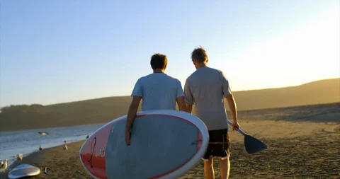 Two paddleboarders walking along the beach. 스톡 동영상 88369902