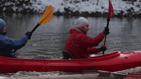 Two paddlers paddle fast down a calm river in a red kayak. Stock-Footage 299033318