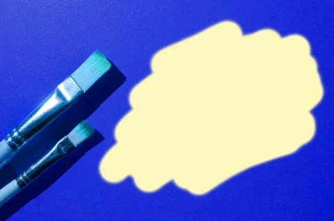 Two paint brushes of different sizes side by side on an blue background. Plac Stock-Fotos