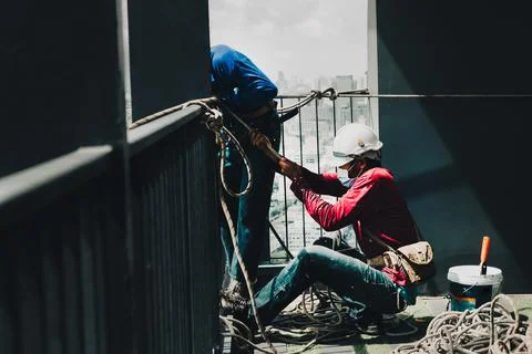 Two painter worker hands pulling the rope working on top of building. Stock Photos