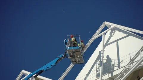 Two painters in Elevator cradle paint walls of old building with white paint. Stock Footage 114058389