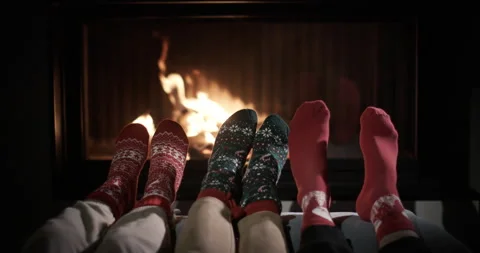 Two pair of legs in warm New Year's socks are heated by the fireplace. Slow Stock Footage 251012964