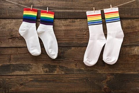 Two pair white socks with rainbow stripes on wooden background hung on clothe Stock Photos