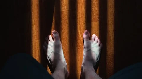Two pairs of bare feet move slowly on a surface with contrasting light and Stock-Footage 338290062