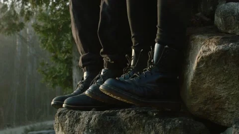 Two Pairs of Black Boots Sitting Down in a Forest Hiking, Close Up Stock Footage 132999363