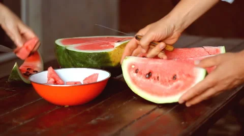 Two pairs of hands cutting fresh watermelon into pieces Stockbeeldmateriaal 41189228