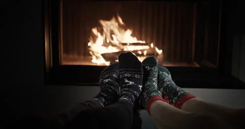 Two pairs of legs dance in the background of a fireplace where a fire burns. Fun Stock Footage 249612501