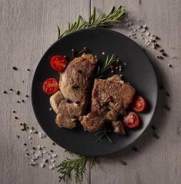 Two pan-seared pork chops rest on a dark gray plate Stock Photos