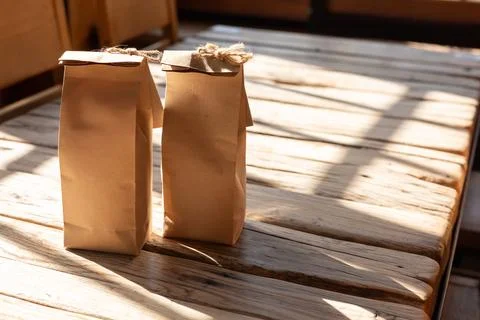 Two paper bags resting on a rustic wooden table illuminated by sunlight in a Stock Photos