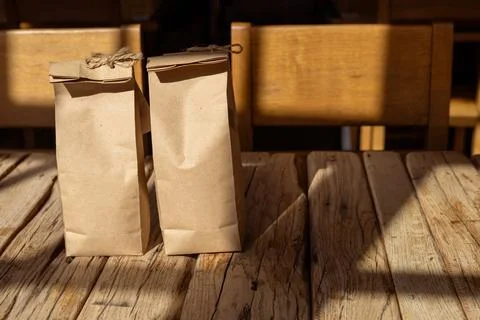 Two paper bags resting on a rustic wooden table illuminated by sunlight in a Stock Photos