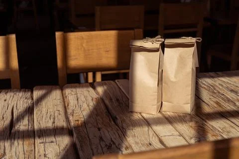 Two paper bags resting on a rustic wooden table illuminated by sunlight in a Stock Photos
