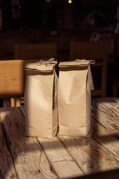 Two paper bags resting on a rustic wooden table illuminated by sunlight in a Stock Photos