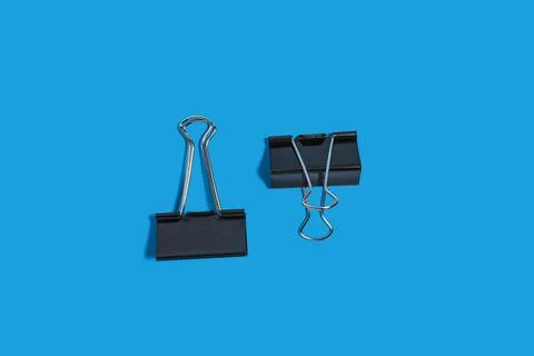 Two paper clips on a blue background Stock Photos