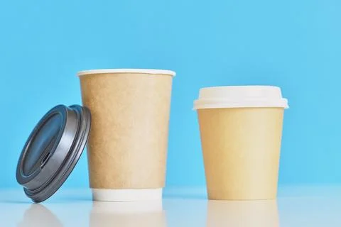 Two paper coffee cups on blue background. Creative mockup image Stock Photos