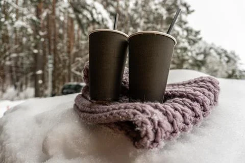 Two paper cups with coffee keep warm on a scarf in the snow, winter love tale Fotos de archivo