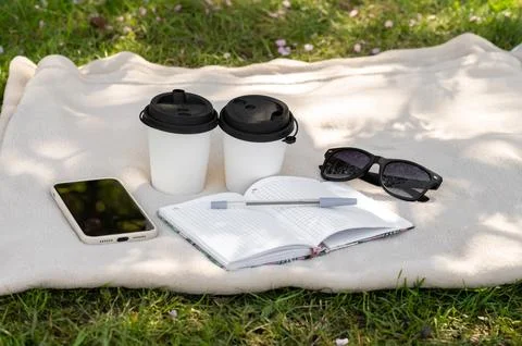 Two paper cups of coffee or tea on a light blanket, a notebook, a pen, glasse Stock Photos