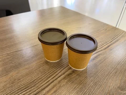 Two paper cups of espresso coffee on a coffee shop table. Coffee to go. Stock Photos