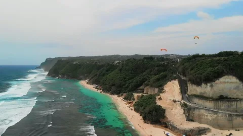 Two parachutists flying over the dense forested hill of the Melasti Beach Video stock 106577390