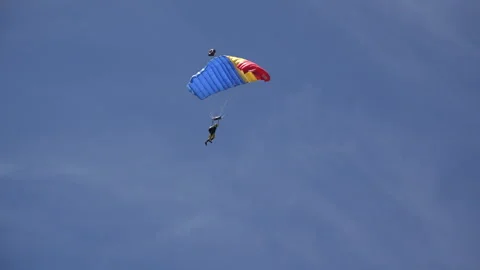 Two paragliders colored in blue-yellow-red on blue sky Stock Footage 318179879