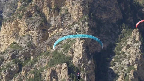 Two paragliders fly into the frame in the background of the cliff Stock Footage 83706149