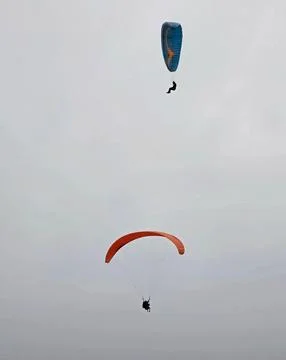 Two Paragliders Flying in the Cloudy Sky Stockfoto's