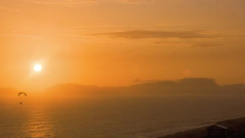 Two paragliders flying under the sun at sunset Stock Footage 277076538