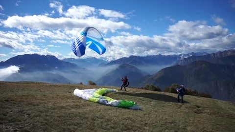 Two paragliders landing on the mountain Stock Footage 76046722
