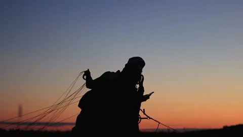 Two paragliders prepare to take off at sunset Stock Footage 197405988