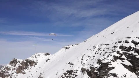 Two paragliders sailing over snow covered mountain Stock Footage 76046754