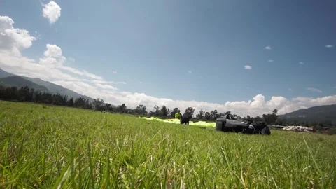 Two paragliders saving the parachute after a paraglide in a green grass 스톡 동영상 133379670