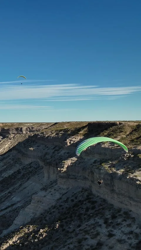 Two paragliding flying over badlands desert area with big cliffs on a sunny d Stock Footage 285145337