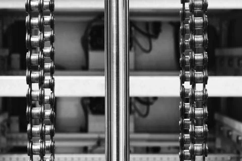 Two parallel metal chains hang vertically inside machine. Cylindrical shaft d Stock Photos