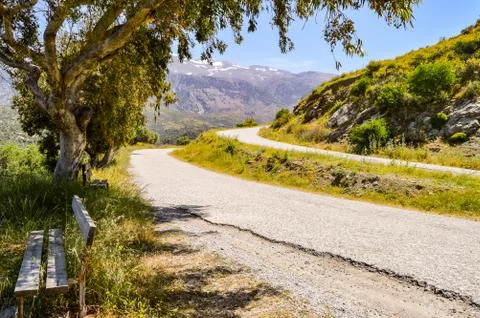 Two parallel mountain roads in Crete with a wooden bench Foto stock