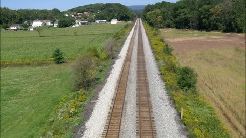 Two parallel railroad tracks passing through the green trees in a village Video stock 109130579