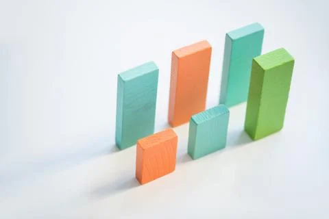 Two parallel rows of blue, orange and green flat wooden bricks making up charts Stock Photos