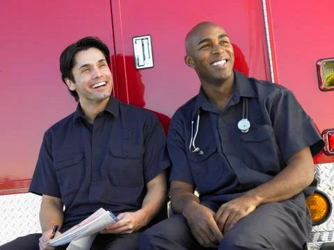 Two paramedics cheerfully doing paperwork, sitting by their ambulance Stock Photos