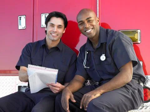 Two paramedics cheerfully doing paperwork, sitting by their ambulance Stock Photos