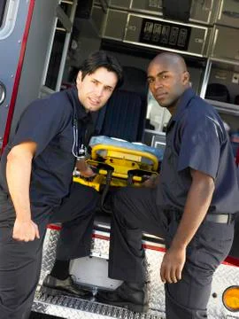 Two paramedics cheerfully removing empty gurney from ambulance Stock Photos