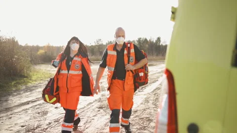 Two paramedics in full equipment walking towards ambulance vehicle Stock Footage 143934406