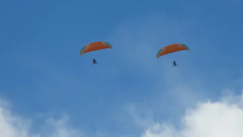 Two paramotor pilots operate personal motorized paragliders soaring high across 스톡 동영상 318201324