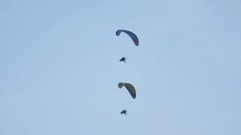 Two paramotors operate clear light blue sky, displaying powered paragliding 스톡 동영상 318202939