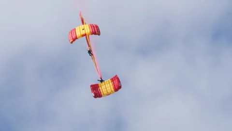 Two paratroopers descend connected by ropes, performing acrobatics during a Stock Footage 311012525